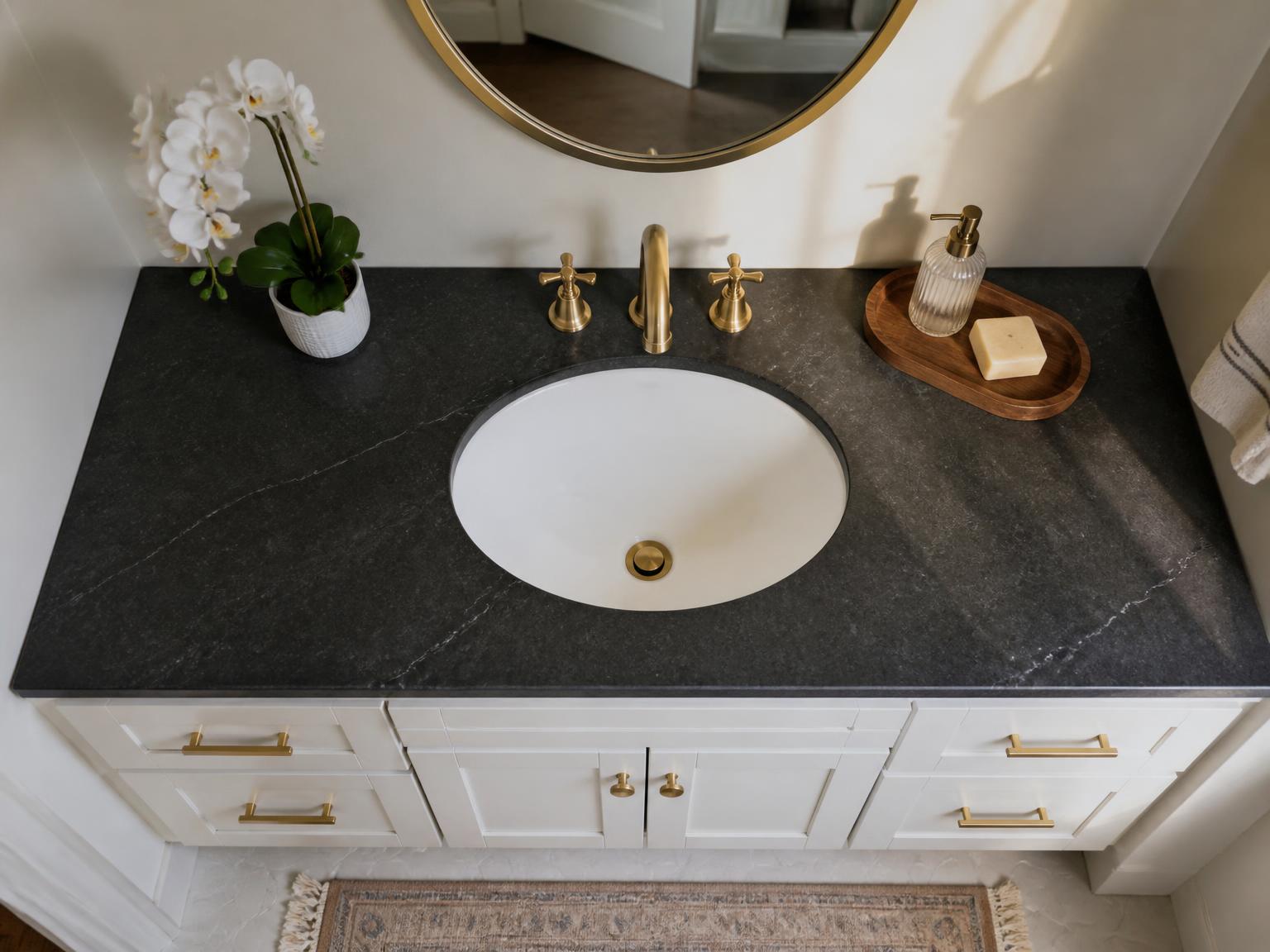 Overhead view of a white oval undermount sink flush in a dark stone-look laminate vanity top